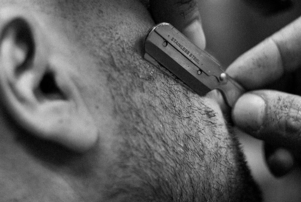 Barber carefully trimming beard with a straight razor