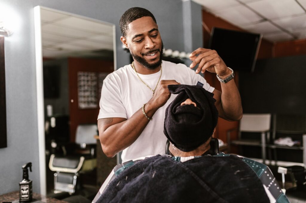 Barber applying hot towel to customer's face for shave